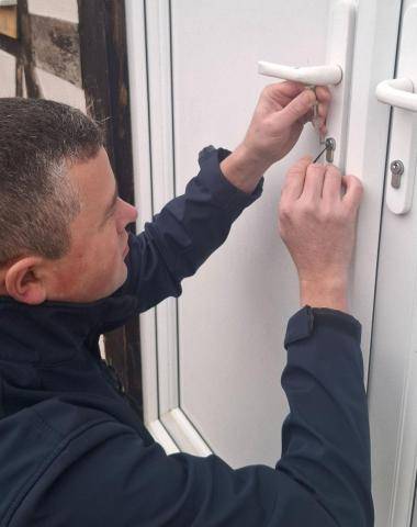 Emergency locksmith picking a lock on a white UPVC door