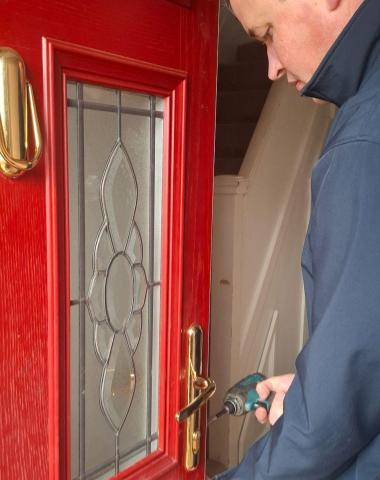 The Parish locksmith assesing a red composite door for lock change and repair services