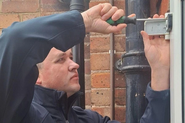 Locksmith adjusting a door hinge as part of a professional door repair.