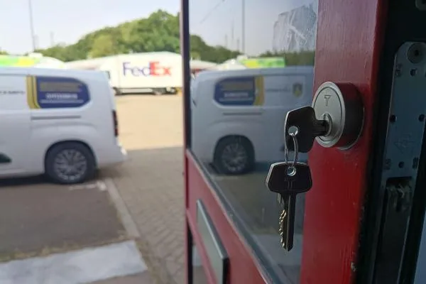 Keys in a commercial entrance door lock with The Parish Locksmith van outside