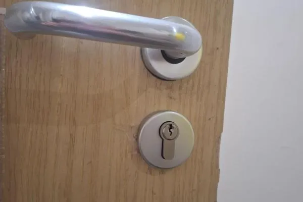 Commercial locksmith in Irchester repairing a cylinder lock on a wooden office door.