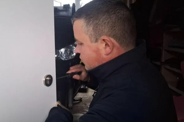 Locksmith fitting a new cylinder to a door as part of a professional lock installation.