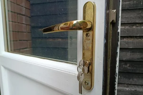 Keys in the lock of a white uPVC door with a gold lever handle in Wellingborough.