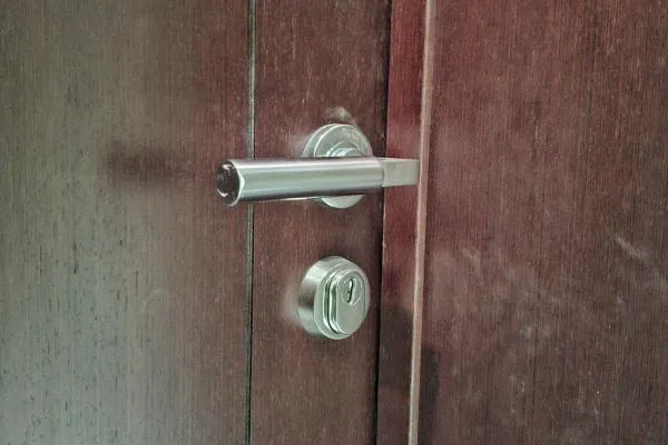 Residential locksmith in Irchester fitting a cylinder lock and lever handle to a wooden door.