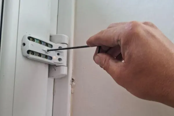 PVC door hinge being adjusted during a door repair