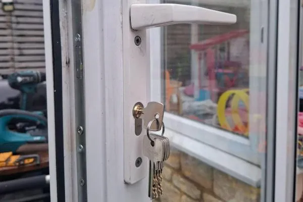 Newly changed cylinder lock and keys on a white conservatory door in Bozeat