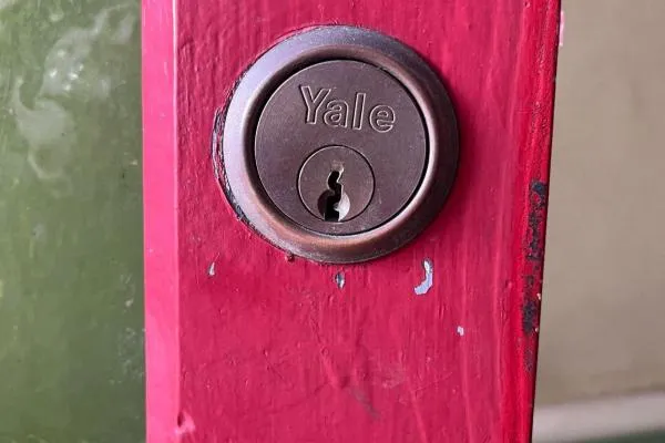 Close-up of a Yale cylinder lock fitted to a red wooden door, illustrating emergency locksmith services in Castle Ashby.