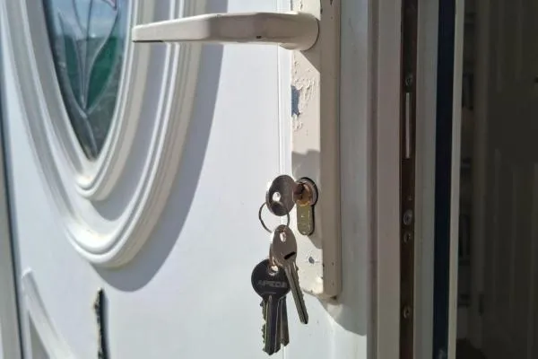 White uPVC front door with keys in a euro cylinder lock, illustrating lock change services in Castle Ashby.