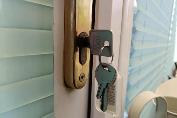 Euro cylinder lock with keys inserted into a uPVC door during lock repair.