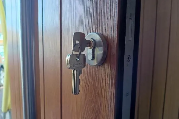 Replacement euro cylinder lock fitted to a woodgrain composite door with new keys.